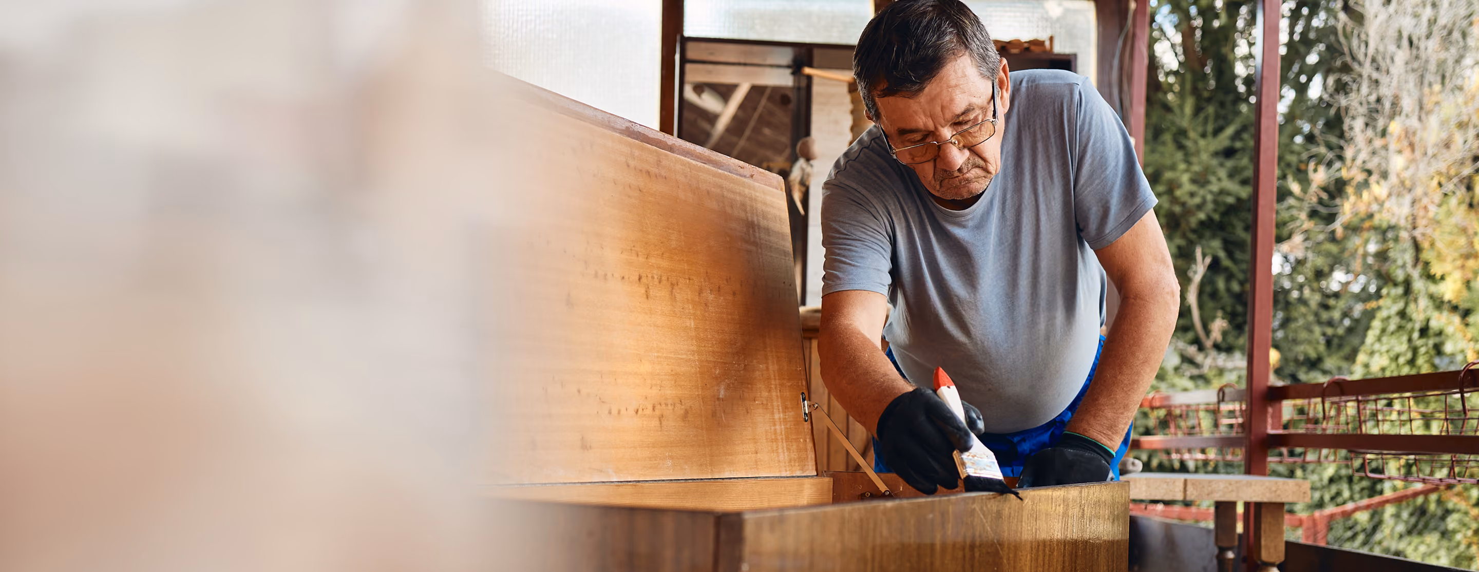 A wood craftsman applying coating to a wooden chest with a brush