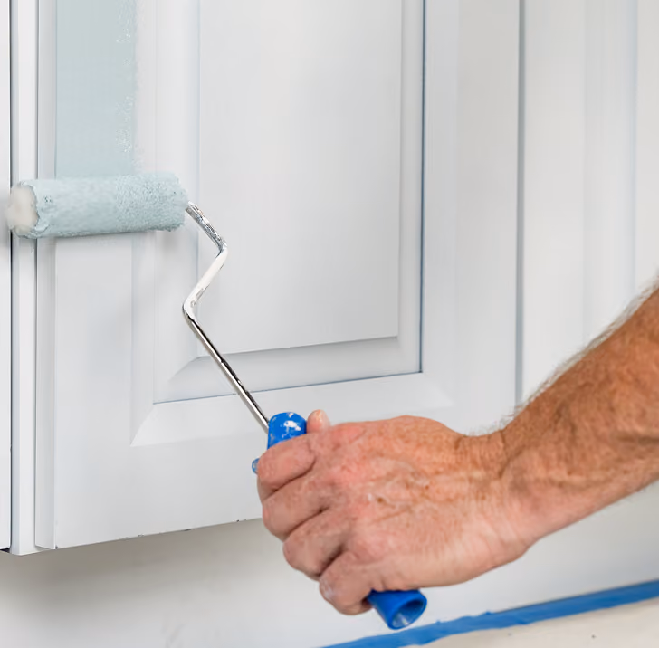 Person applying paint to a kitchen cabinet
