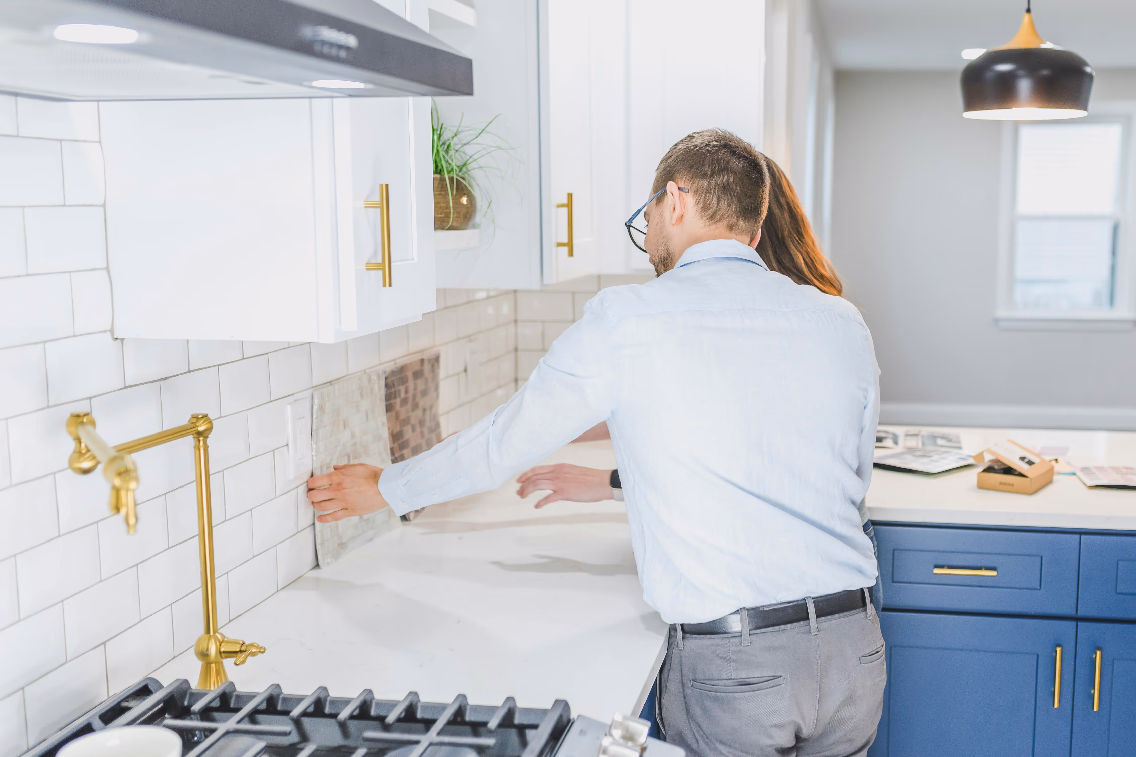 Interior designer in white sweater reviewing fabric samples and materials at kitchen counter
