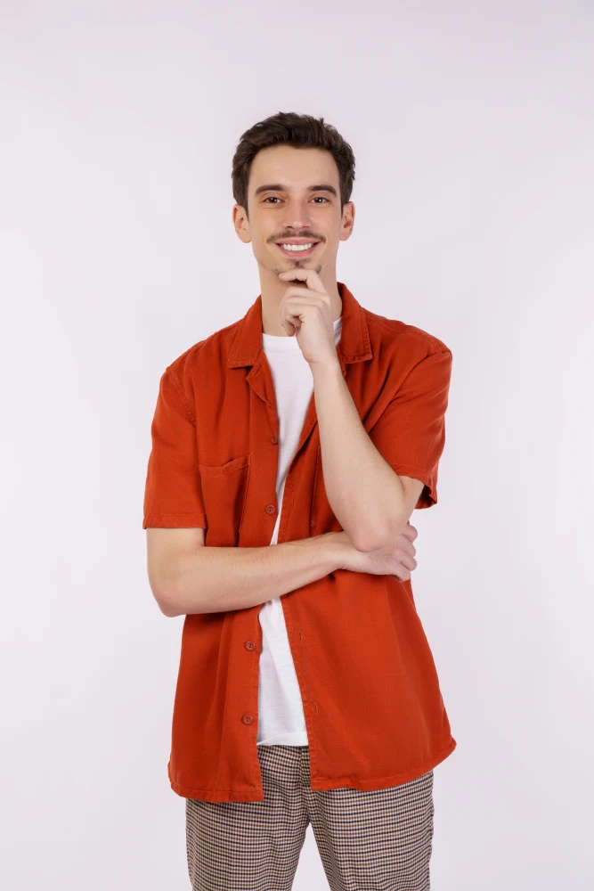 Portrait of man in red shirt smiling with crossed arms.