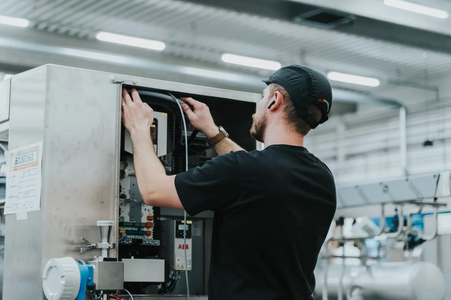 Technician adjusting components inside industrial ice cream machinery.
