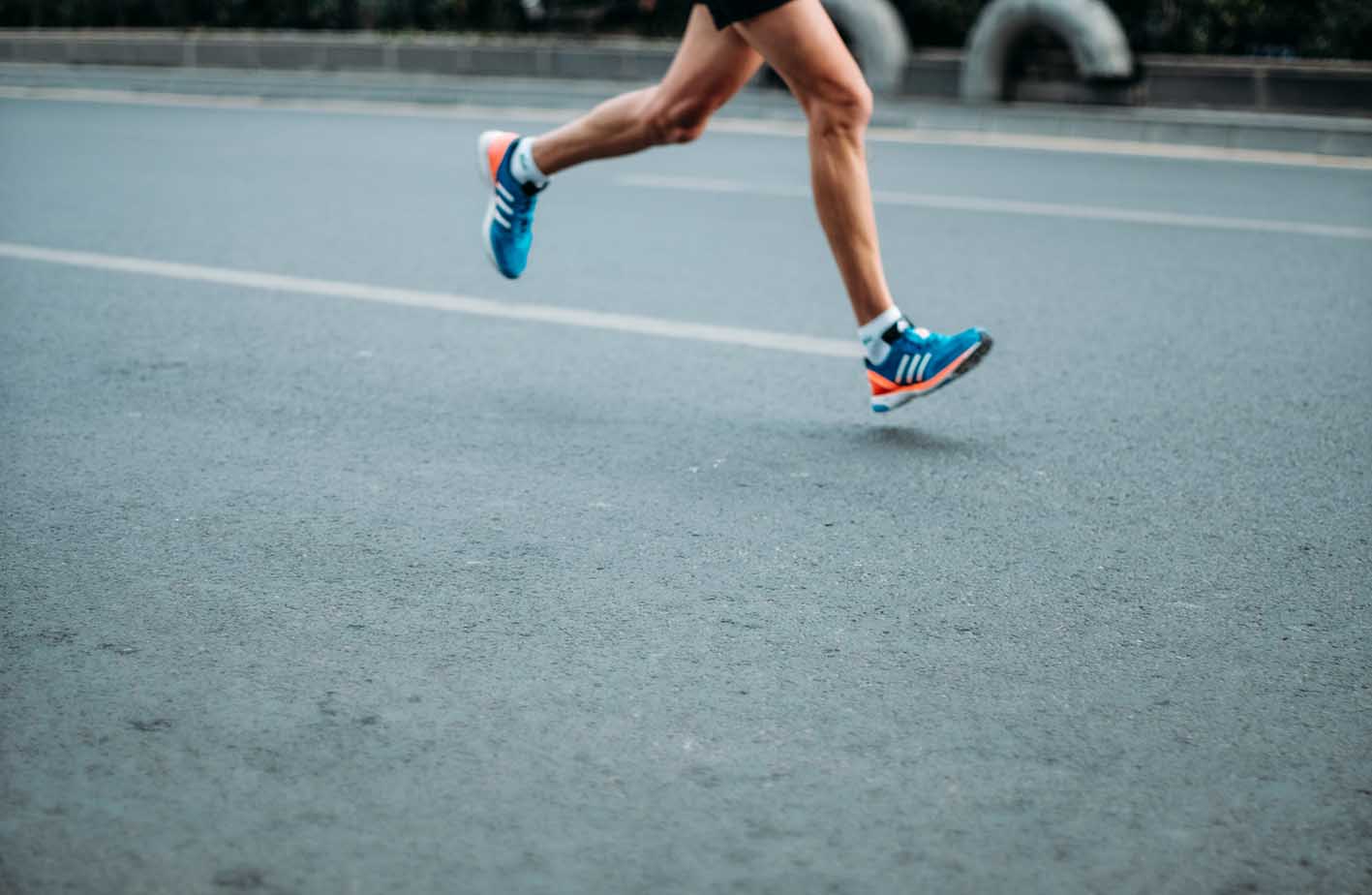 Beine einer Person beim Joggen auf einer Straße
