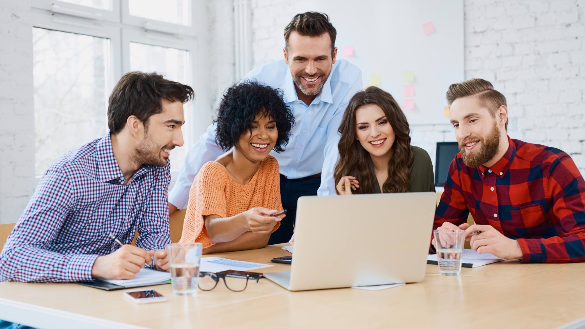 Un groupe de professionnels de tout âge souriants réunis autour d'un bureau lors d'un atelier de formation