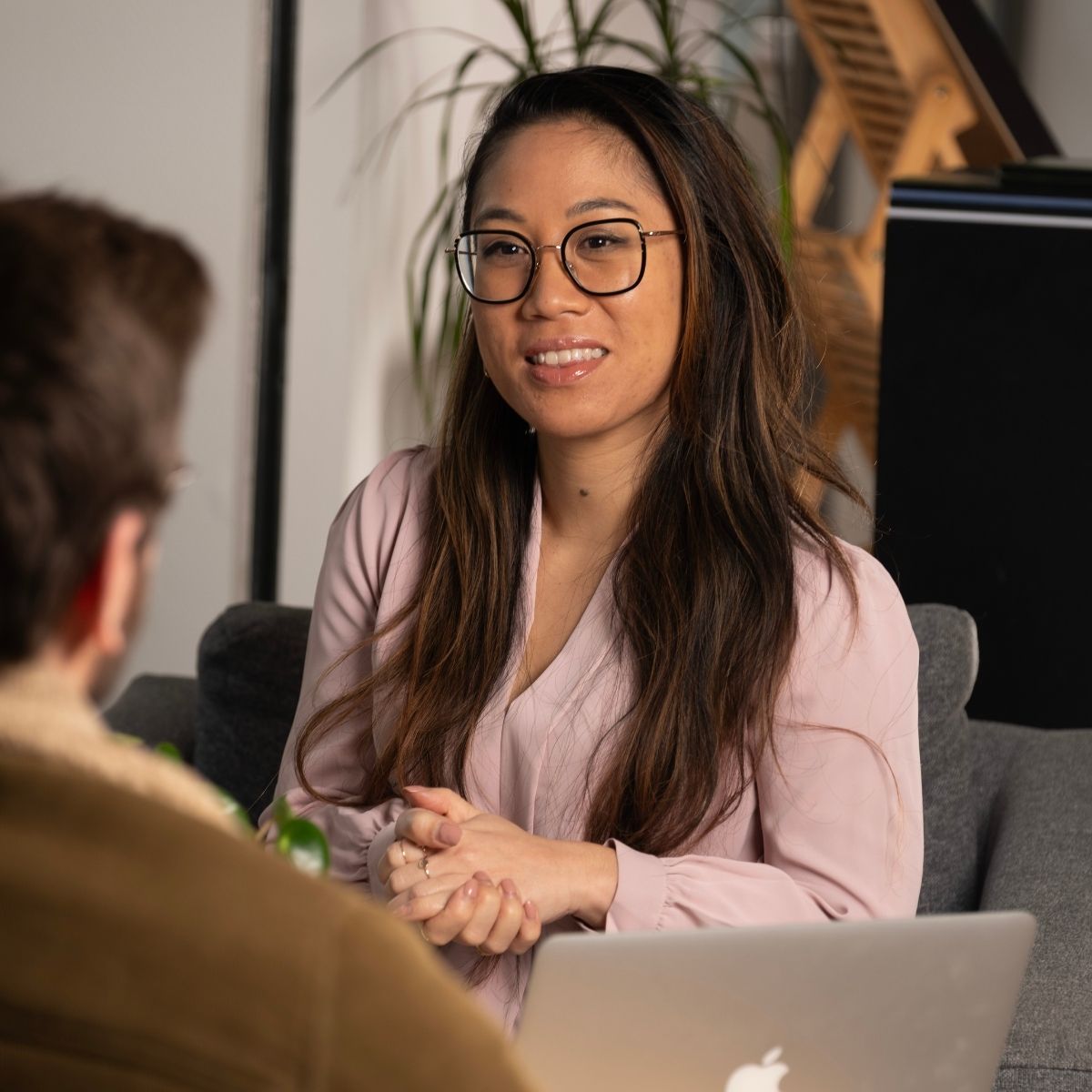Visouda Luangkhot souriante, assise dans un fauteuil, en plein audit d'un client pour comprendre ses besoins de formation