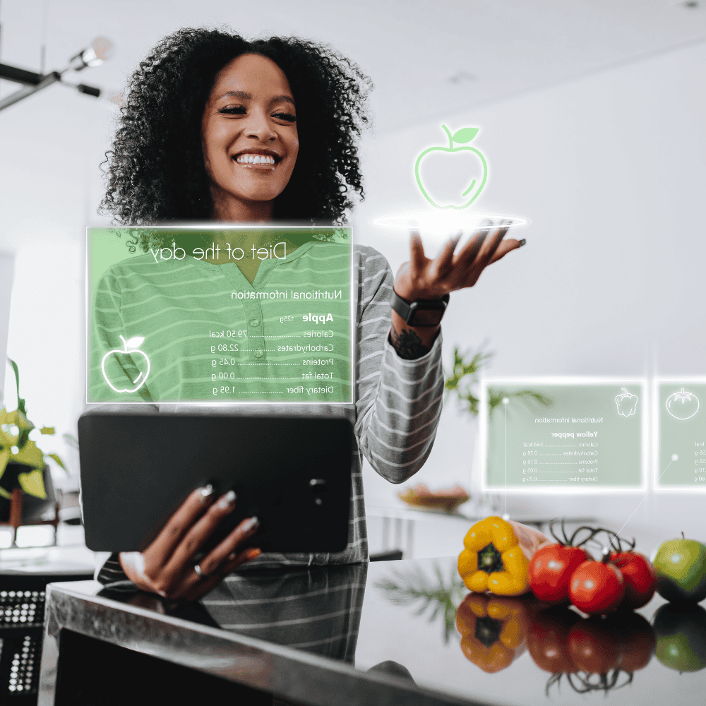 Smiling woman holding a tablet with digital nutrition info and apple icon hovering over her hand in a kitchen with fresh vegetables on the counter.