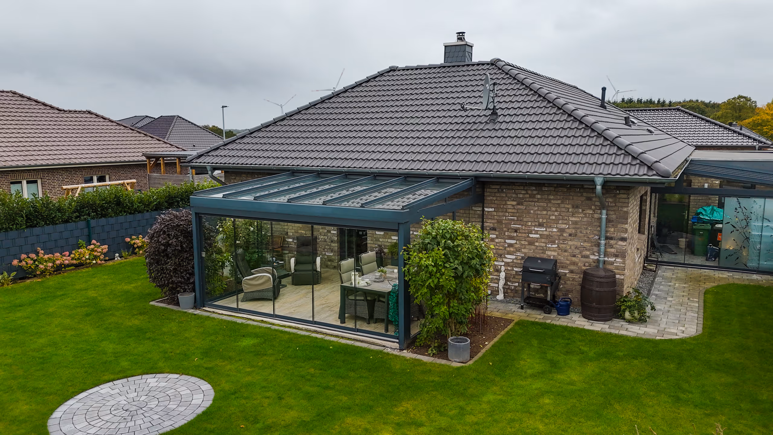 Moderner Ausstellungsraum mit Sitzbereich aus grauen Rattanstühlen und Glastrennwand, beleuchtet mit blauen LED-Lichtern.