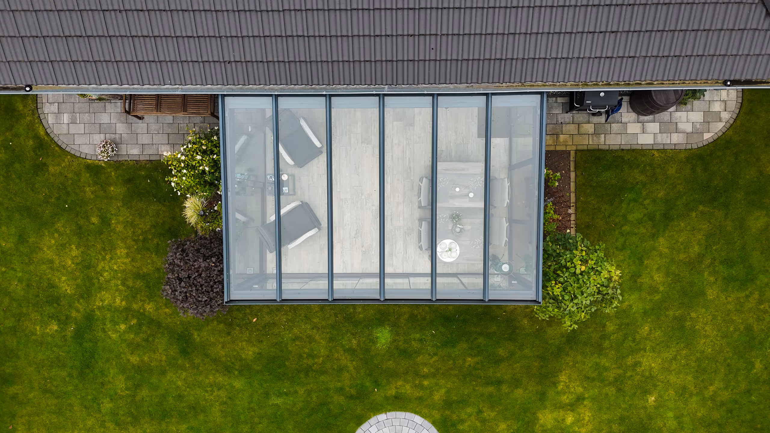 Moderner Ausstellungsraum mit Sitzbereich aus grauen Rattanstühlen und Glastrennwand, beleuchtet mit blauen LED-Lichtern.