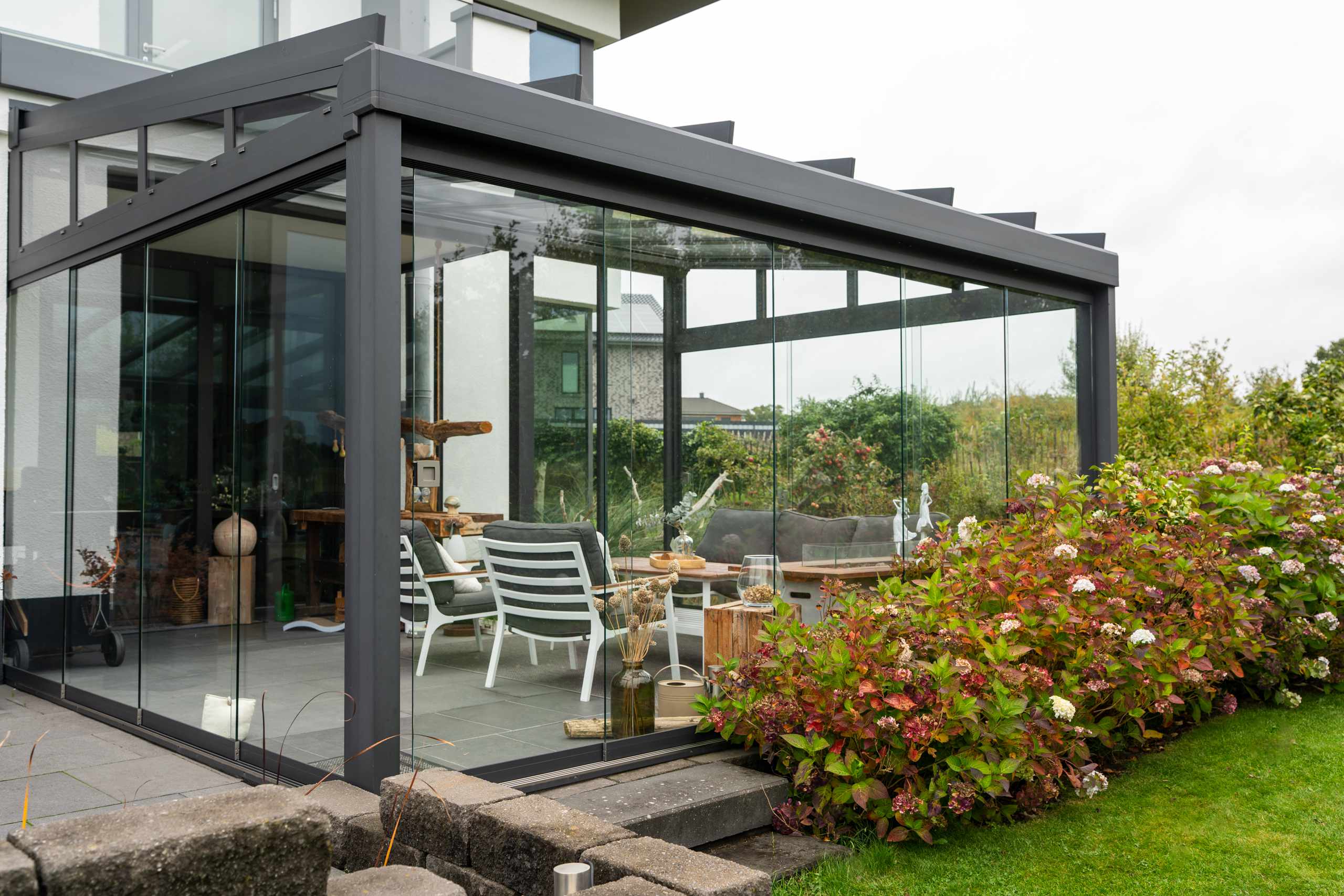 Moderner Ausstellungsraum mit Sitzbereich aus grauen Rattanstühlen und Glastrennwand, beleuchtet mit blauen LED-Lichtern.