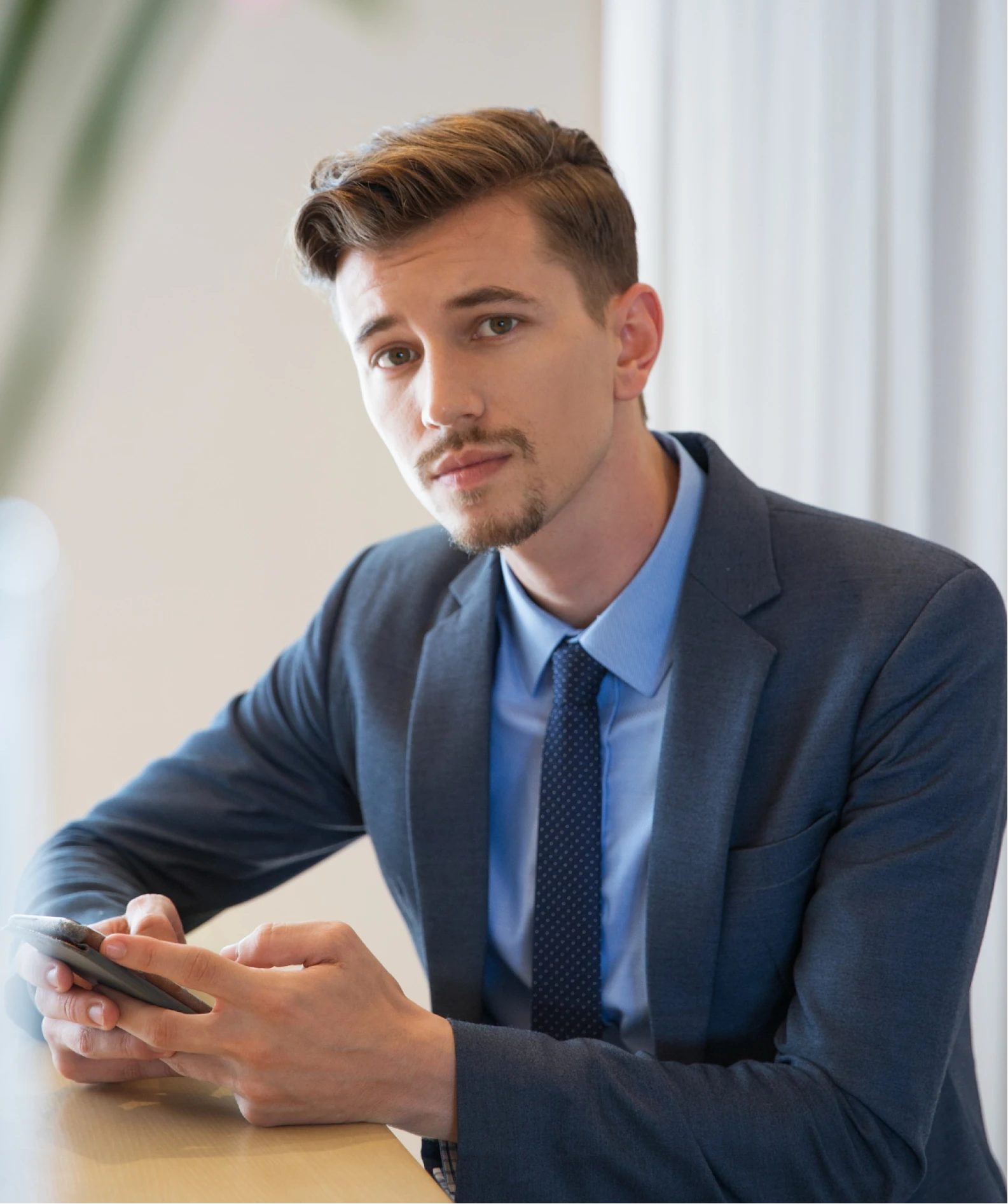 A man sitting at a table looking at his cell phone.