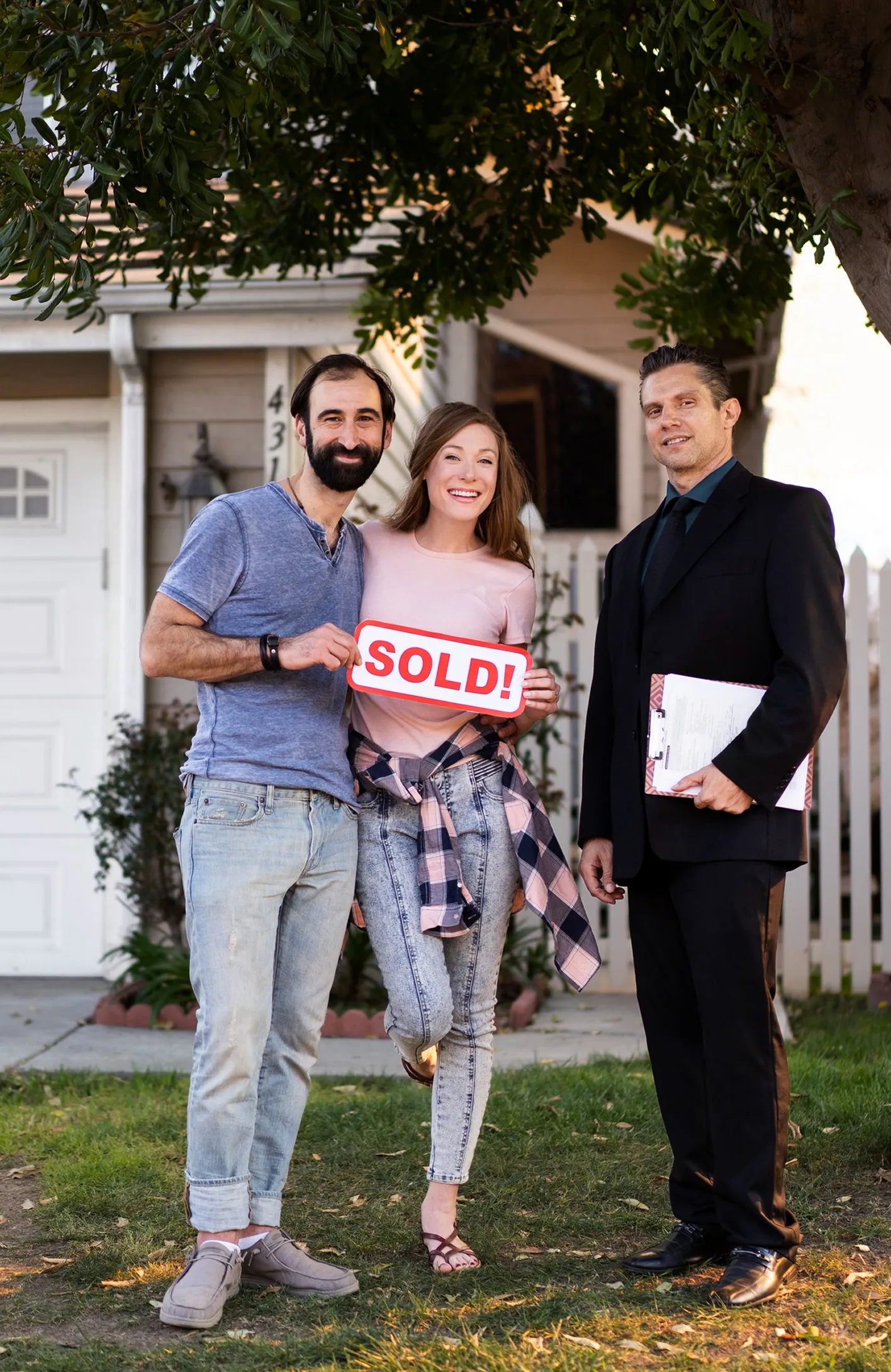 Two men and a woman holding a sold sign.