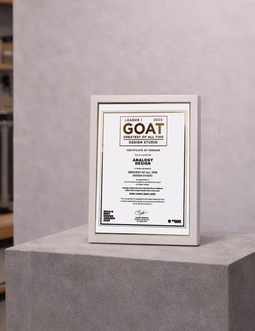 Framed certificate award titled GOAT Greatest of All Time Design Studio for Analogy Design on a gray pedestal.