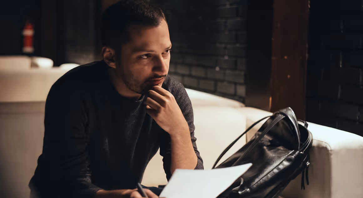 a man sitting at a table with a pen and paper