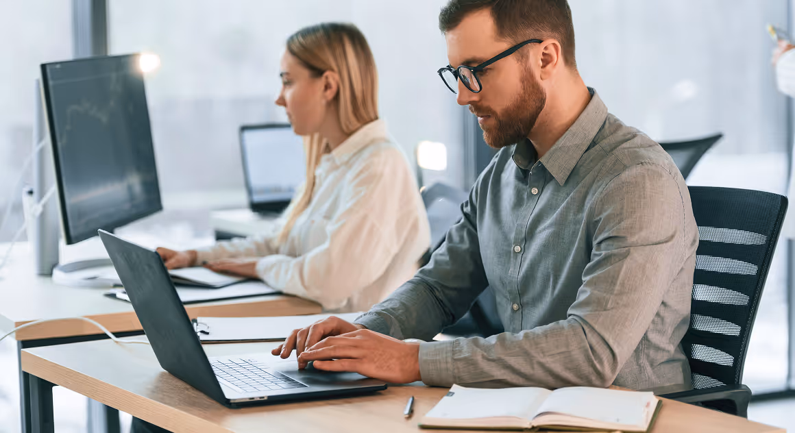 a man and woman sitting at desks using laptops