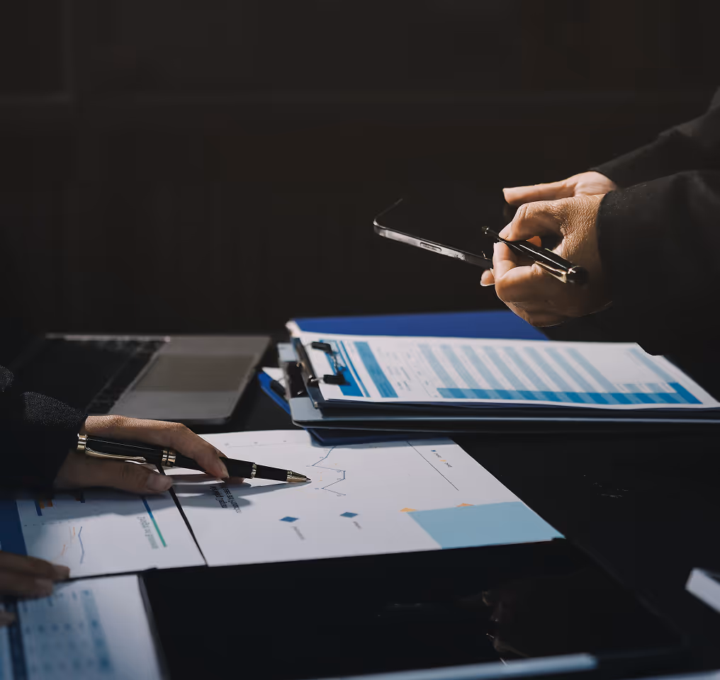 a person holding a pen and writing on papers