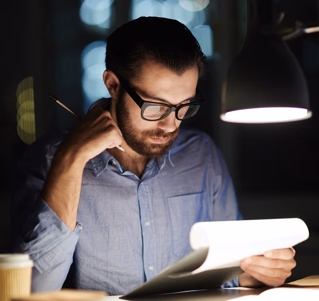 a man holding a pen and looking at a paper