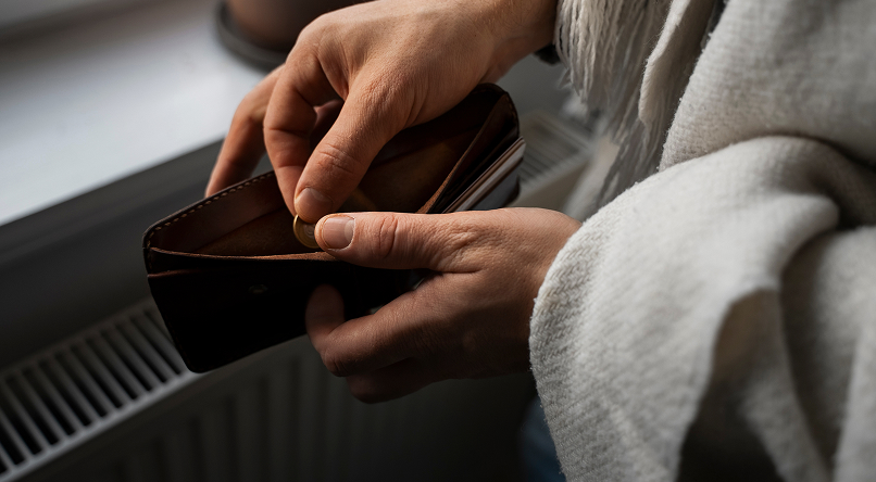 Person holding an open brown leather wallet and counting coins inside.