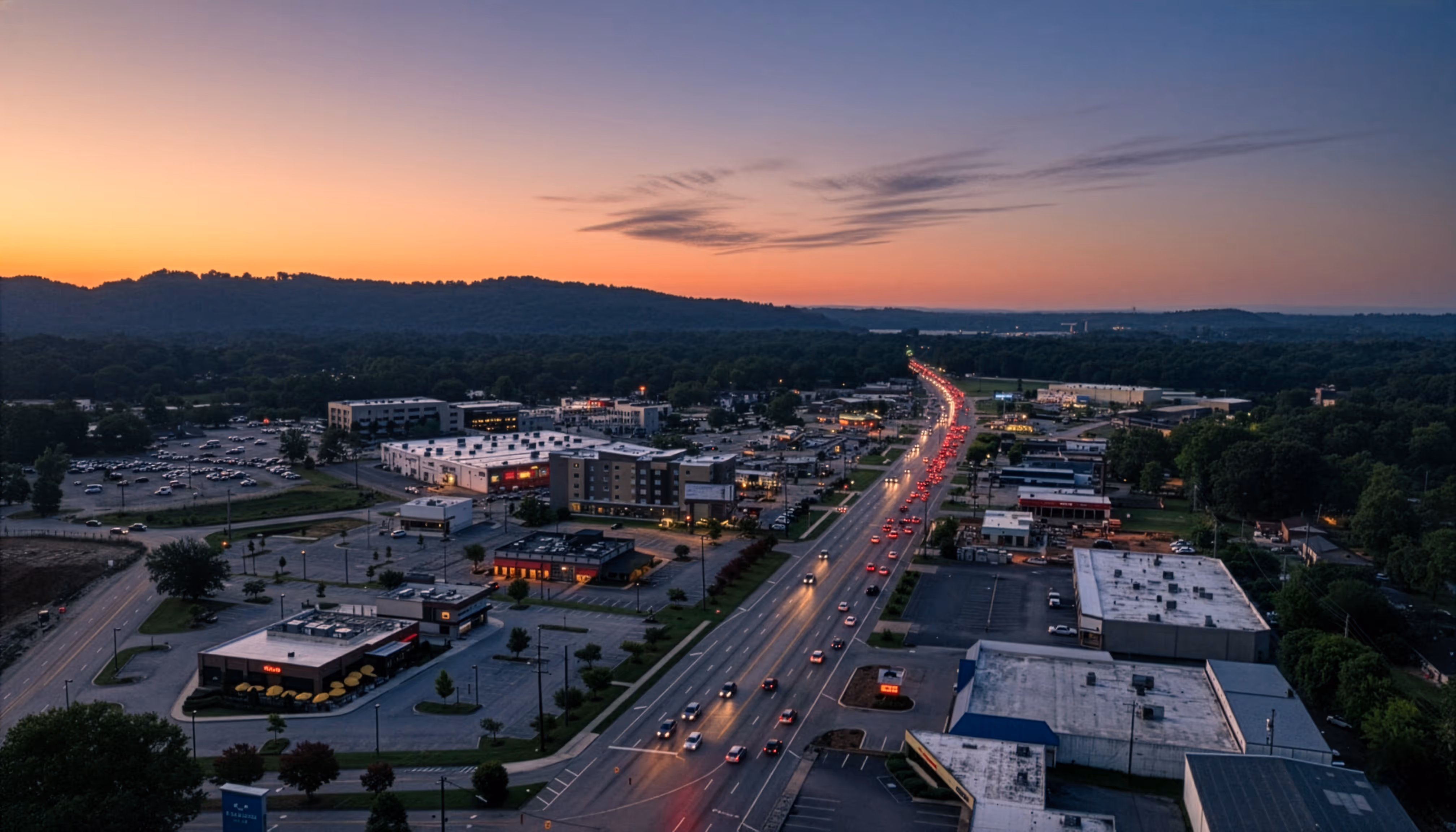 Aerial view of Highway 153 in Hixson TN at sunset, highlighting shopping centers, restaurants, and evening traffic along the main commercial corridor.