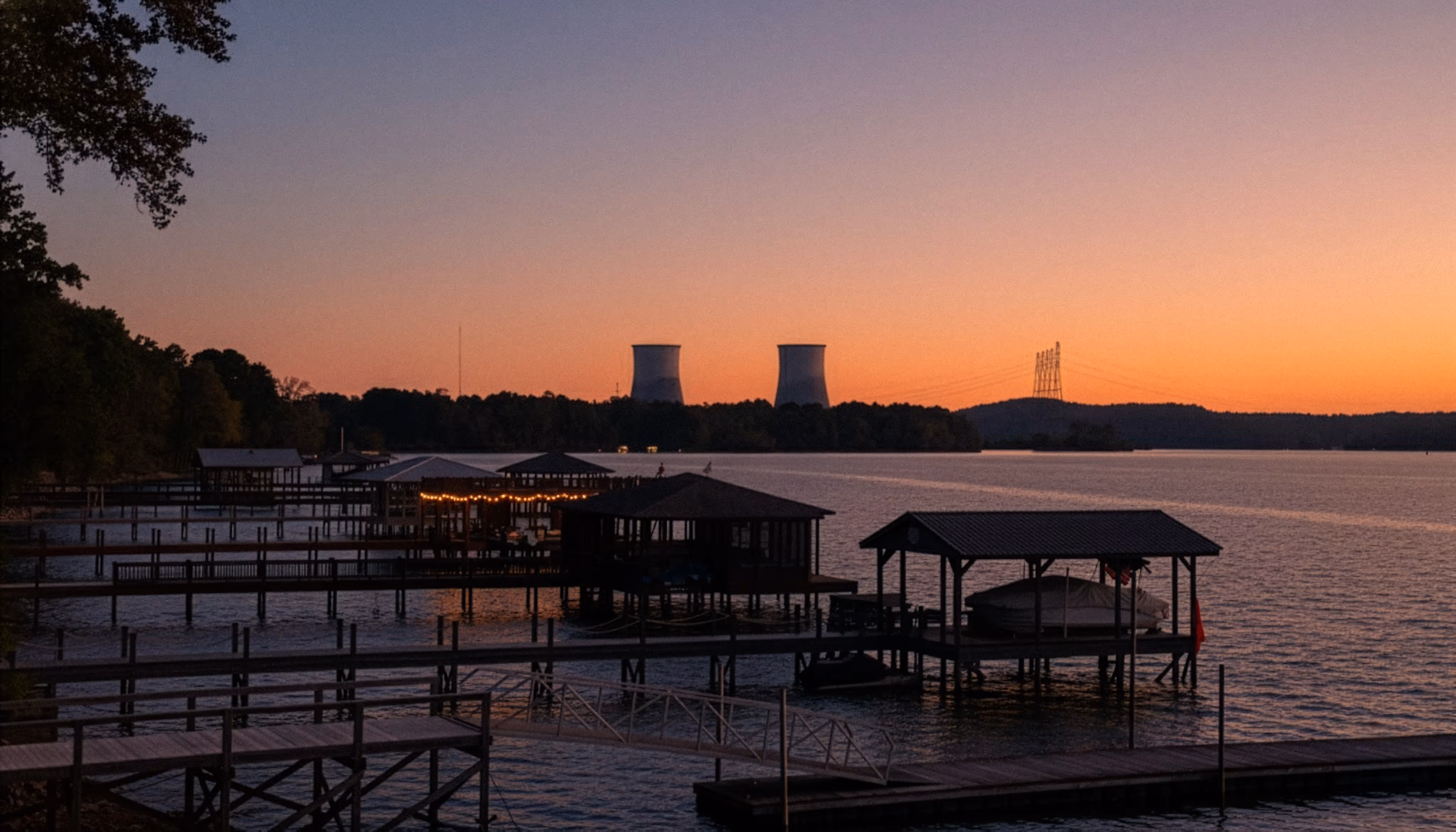 Hidden Harbor Marina at sunrise in Soddy-Daisy, Tennessee, featuring calm lakefront docks and a distant view of the Sequoyah Nuclear Plant.