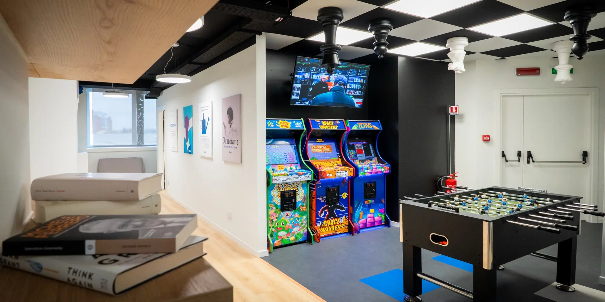 Ufficio moderno con cabinati arcade, un calcio balilla e opere d’arte alle pareti.