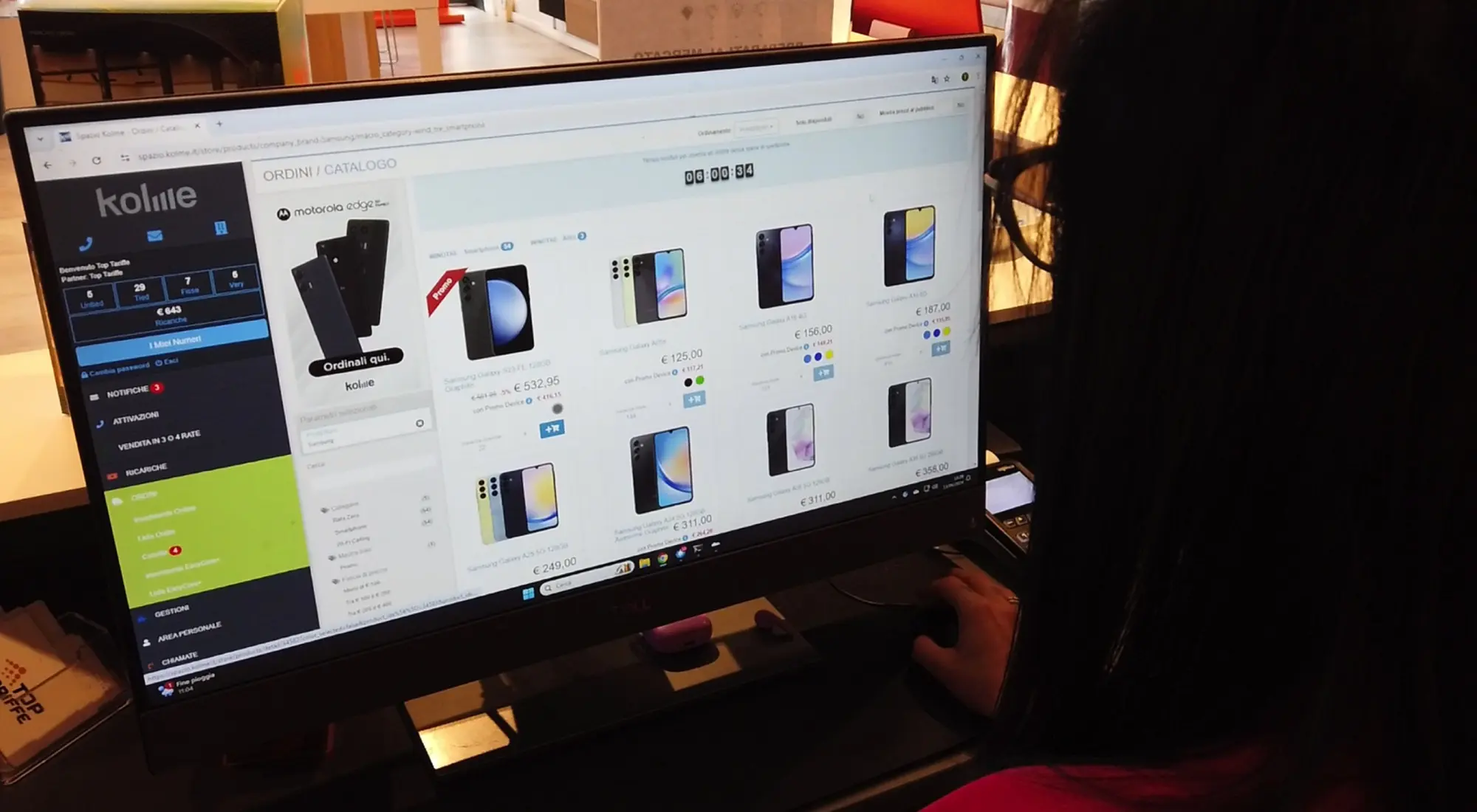 Operatrice consulta il portale Kolme su un monitor, con il catalogo ordini di smartphone Samsung aperto a schermo