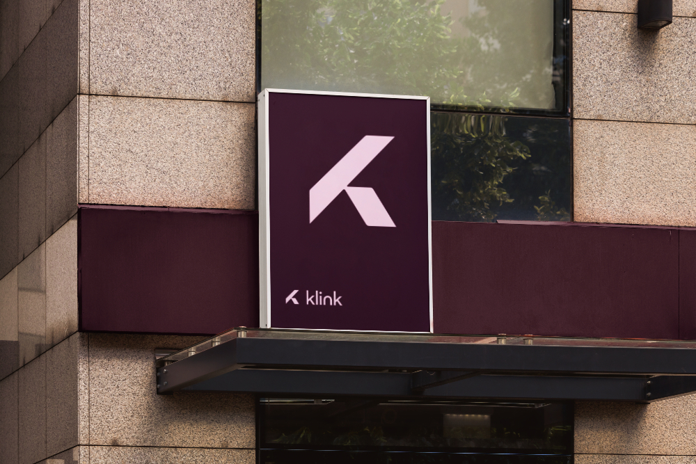 Klink skilt med K-symbolet på mørk plomme bakgrunn over en inngang