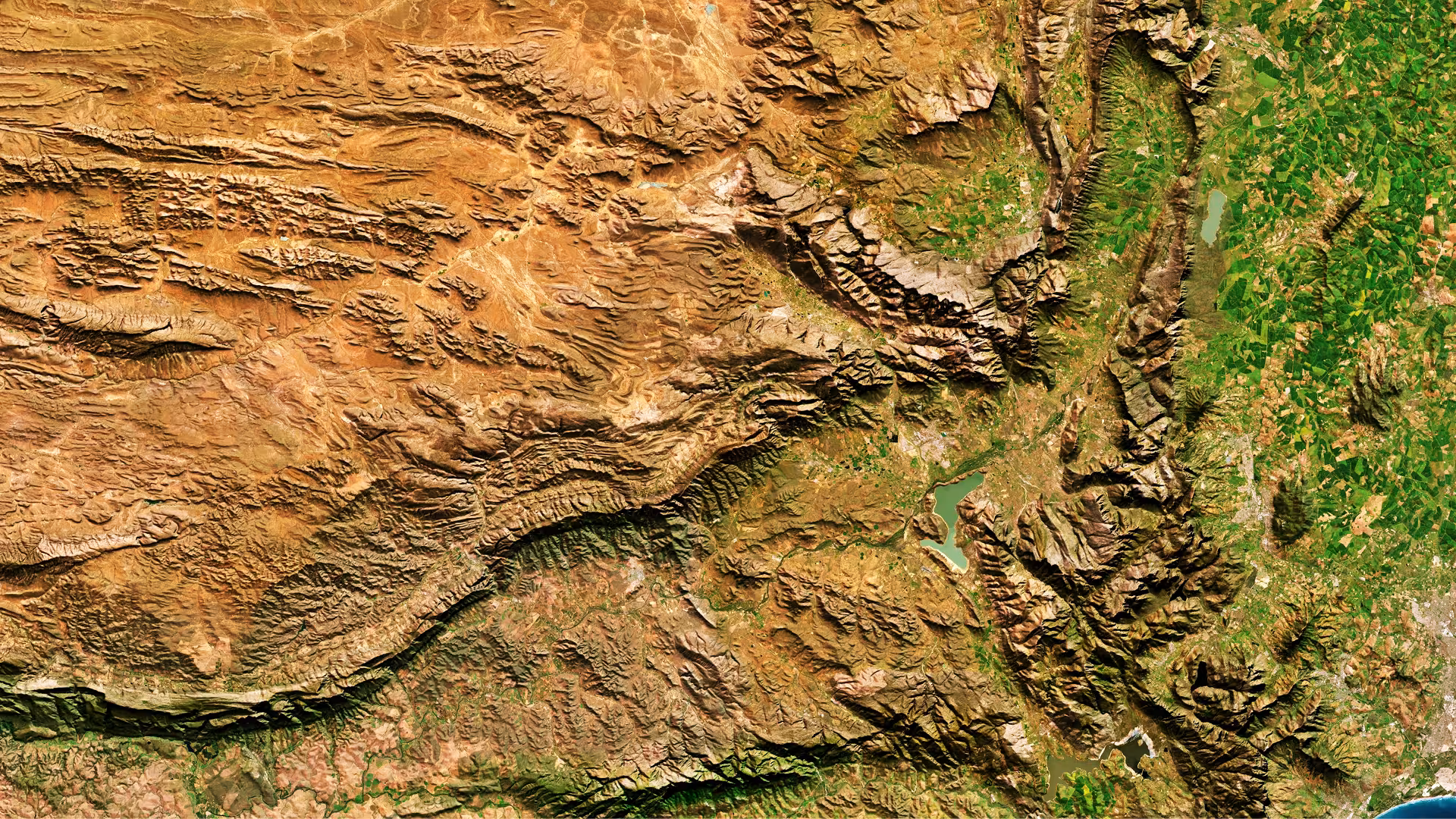 Satellite image of a landscape including rocky outcrops, lakes, green fields and urban environment. 