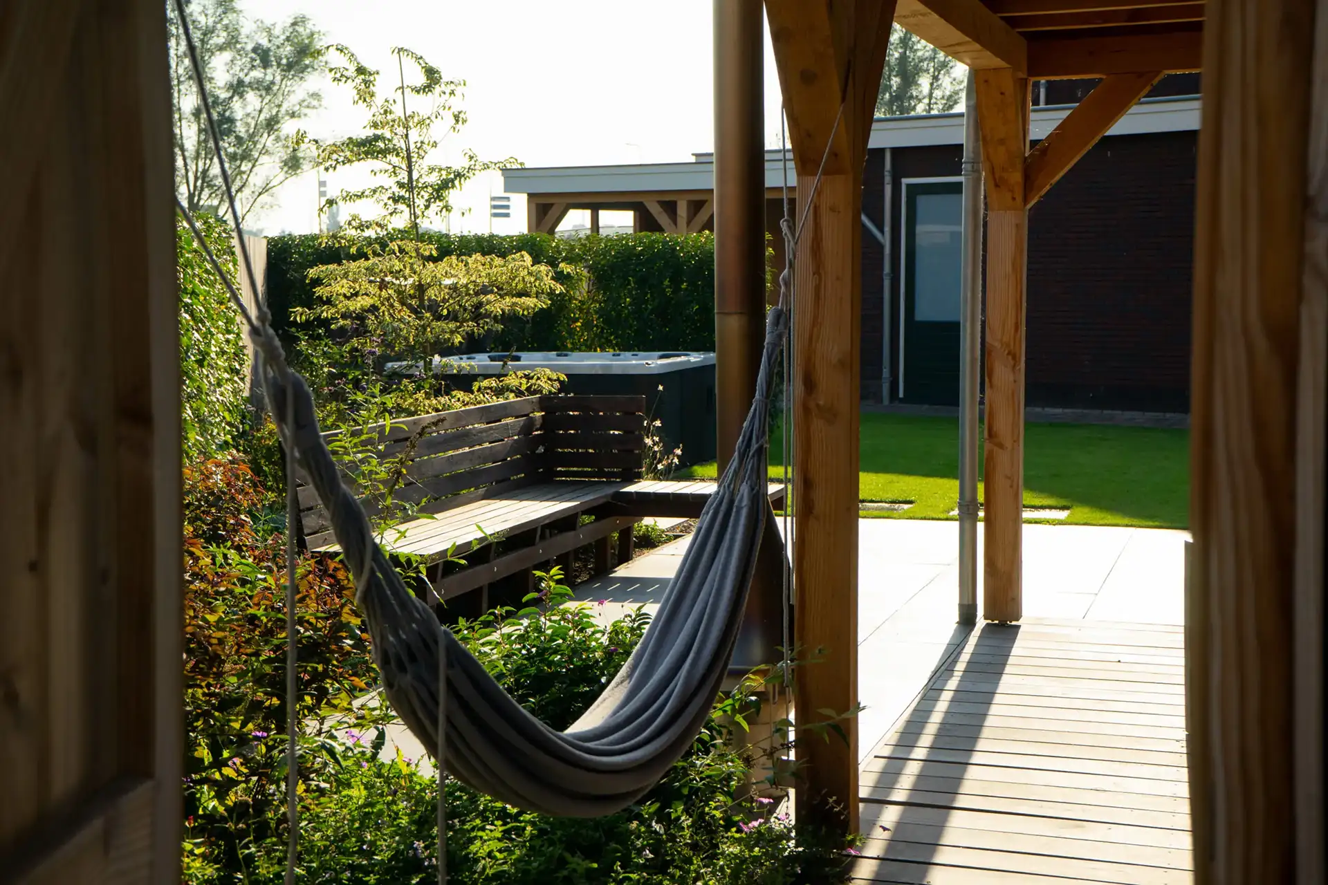 Een tuin om heerlijk in te ontspannen. De strakke basis is gecombineerd met rijke, groene elementen zoals fruitbomen en bloeiende borders. De jacuzzi maakt het plaatje compleet: een plek waar genieten centraal staat.