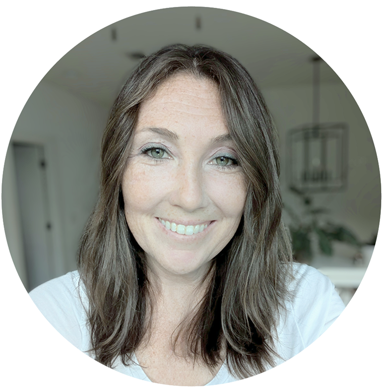 Smiling woman with long brown hair and green eyes wearing a white top in a softly blurred indoor setting. Her name is Nicole Beck