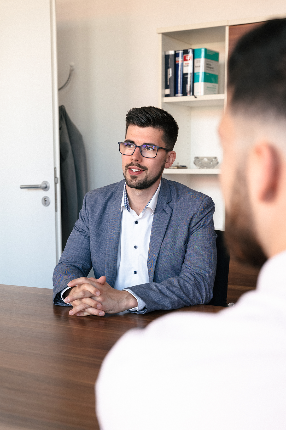 Kilian Kopsch sitzt im Büro an einem Tisch und führt ein Gespräch mit einem Teammitglied.