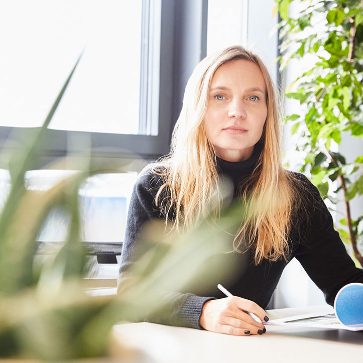 Frau mit langen blonden Haaren arbeitet konzentriert an einem Tisch.