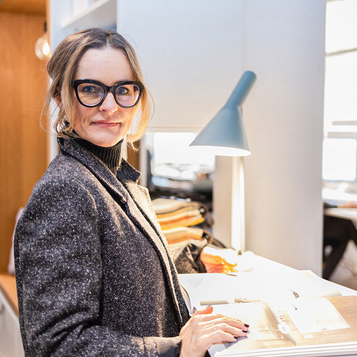 Frau mit Brille arbeitet konzentriert an einem Schreibtisch.