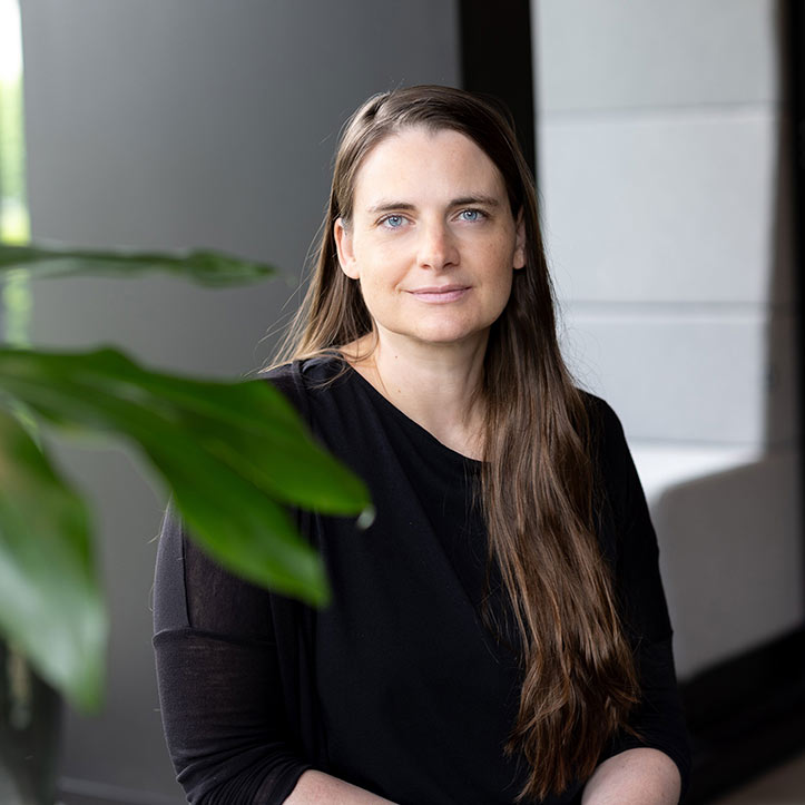 Frau mit langen Haaren steht vor einer Pflanze im Büro.