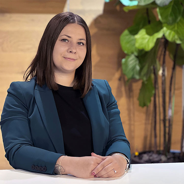 Frau mit dunklem Haar lächelt selbstbewusst in modernem Büro.