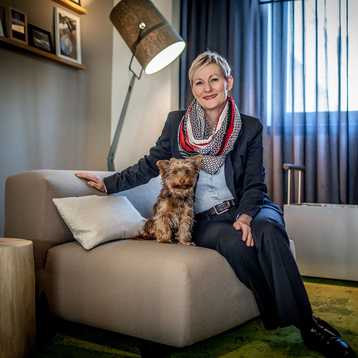 Frau mit Hund sitzt entspannt auf einem Sofa im Büro.