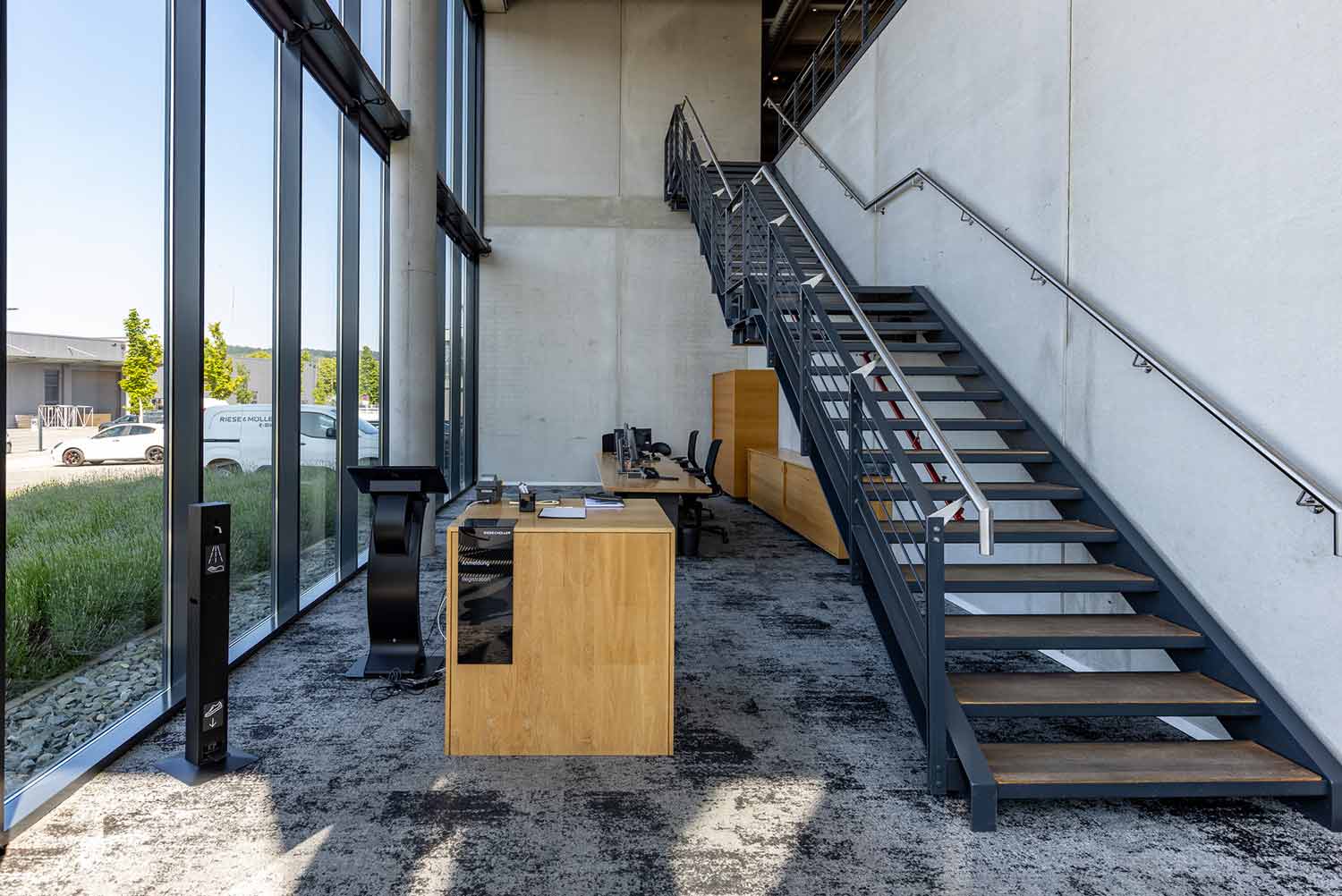 Heller Eingangsbereich mit Glastreppenhaus und modernem Industriedesign.