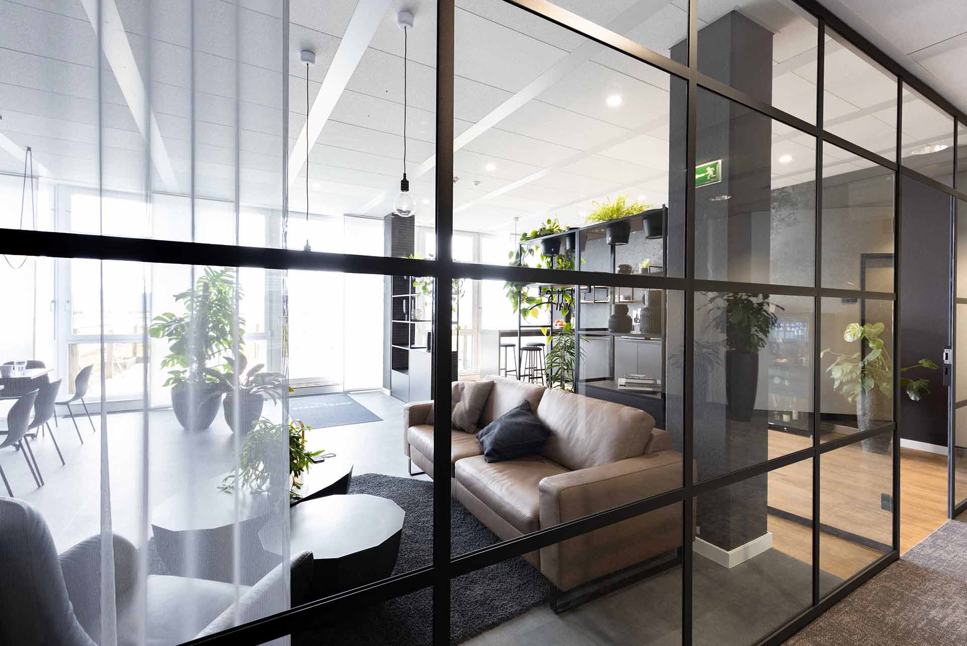 Offene Lounge mit Glaswänden, bequemen Sitzmöbeln und natürlichem Licht.