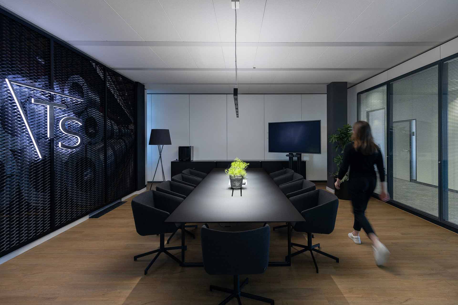 Großer Konferenzraum mit dunklem Tisch, Glaswänden und künstlerischer Wandgestaltung.