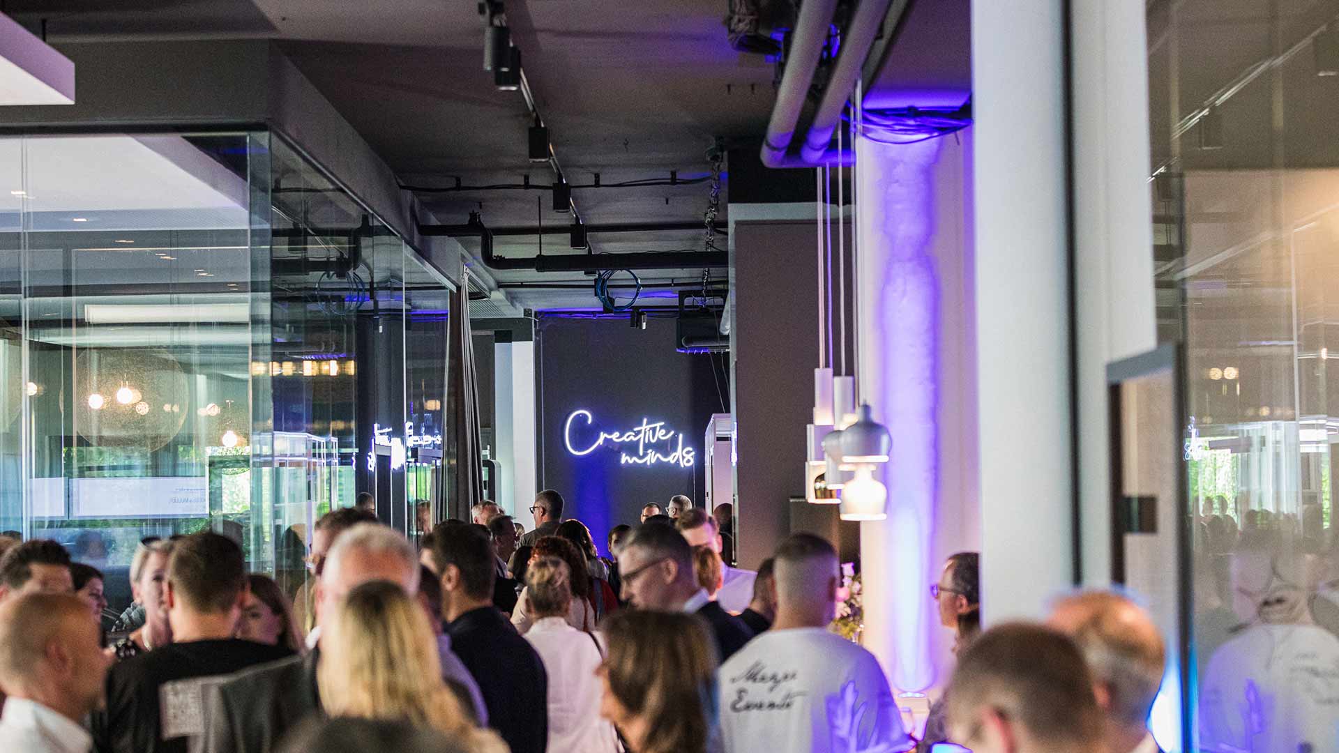 Belebte Abendveranstaltung in modernem Innenraum mit stimmungsvoller Beleuchtung.

