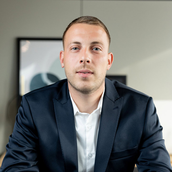 Geschäftsmann im Anzug blickt selbstbewusst in die Kamera.