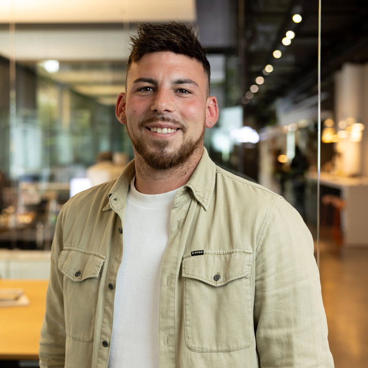 Mann in Freizeitkleidung steht in offenem Büro mit warmem Licht.