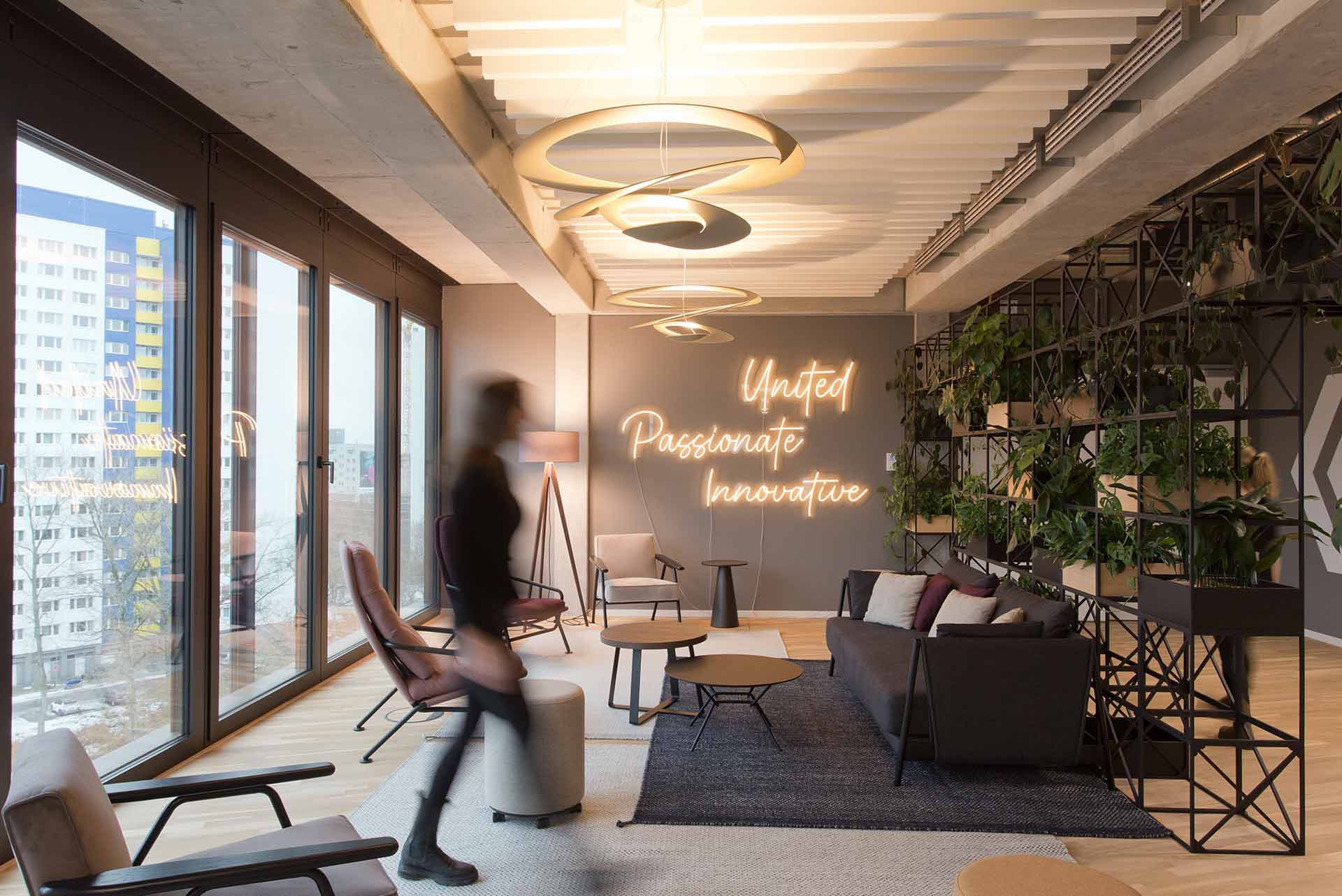 Stilvolle Büro-Lounge mit Pflanzen, Sofas und großem Fensterbereich.