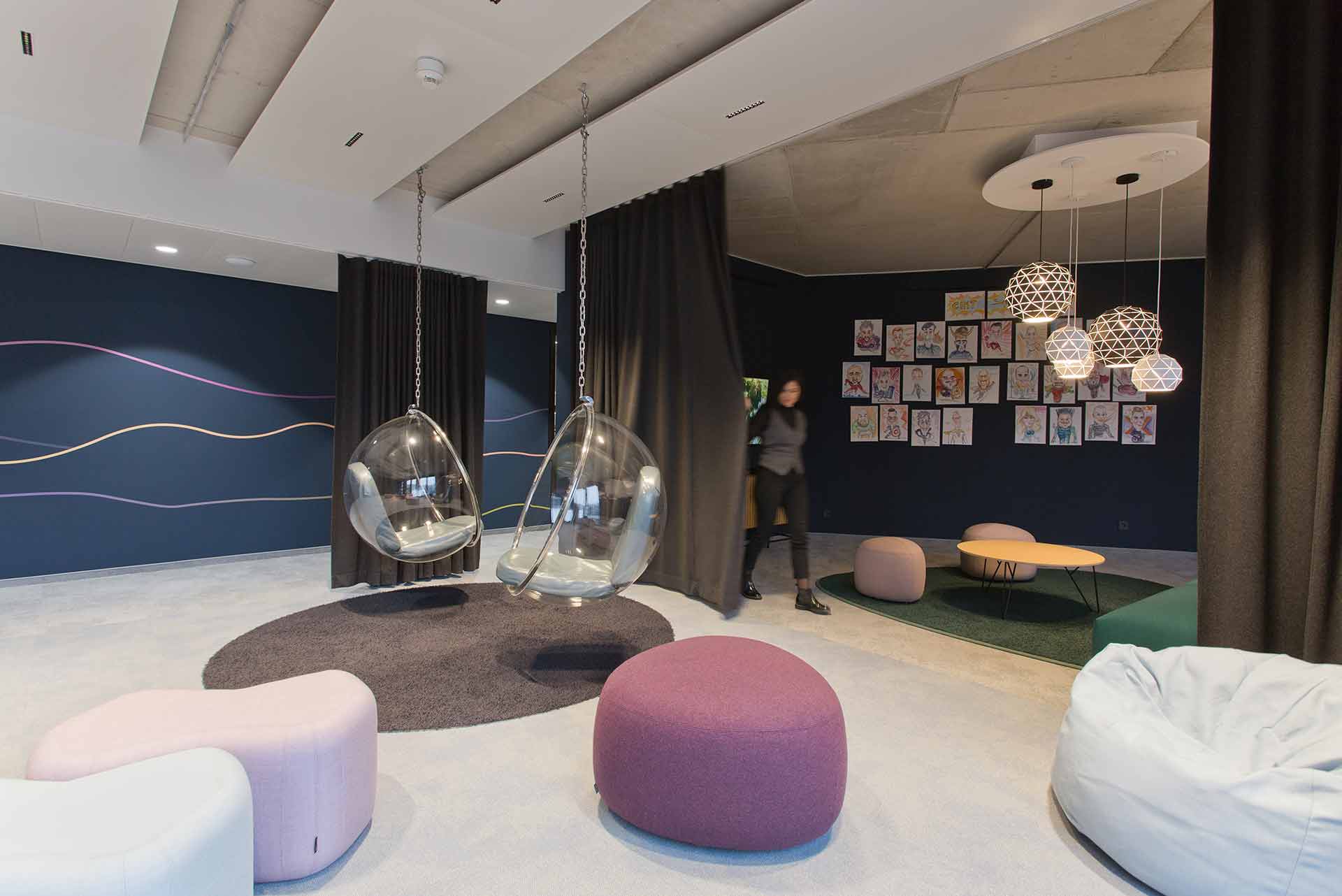 Kreativer Workspace mit Lounge-Ecke und hängenden Sitzmöbeln.