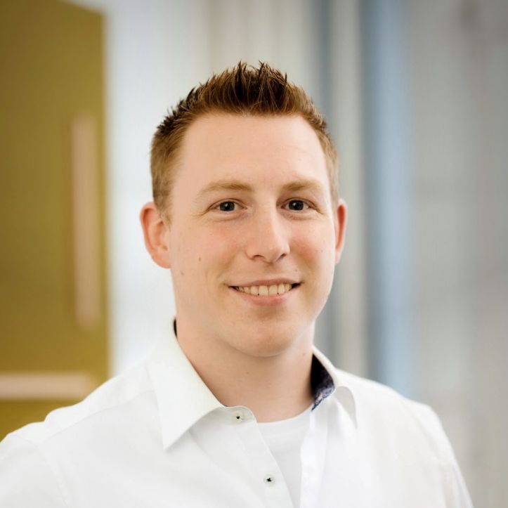 Portrait eines Mannes mit braunen kurzen Haaren. Er lächelt in die Kamera.