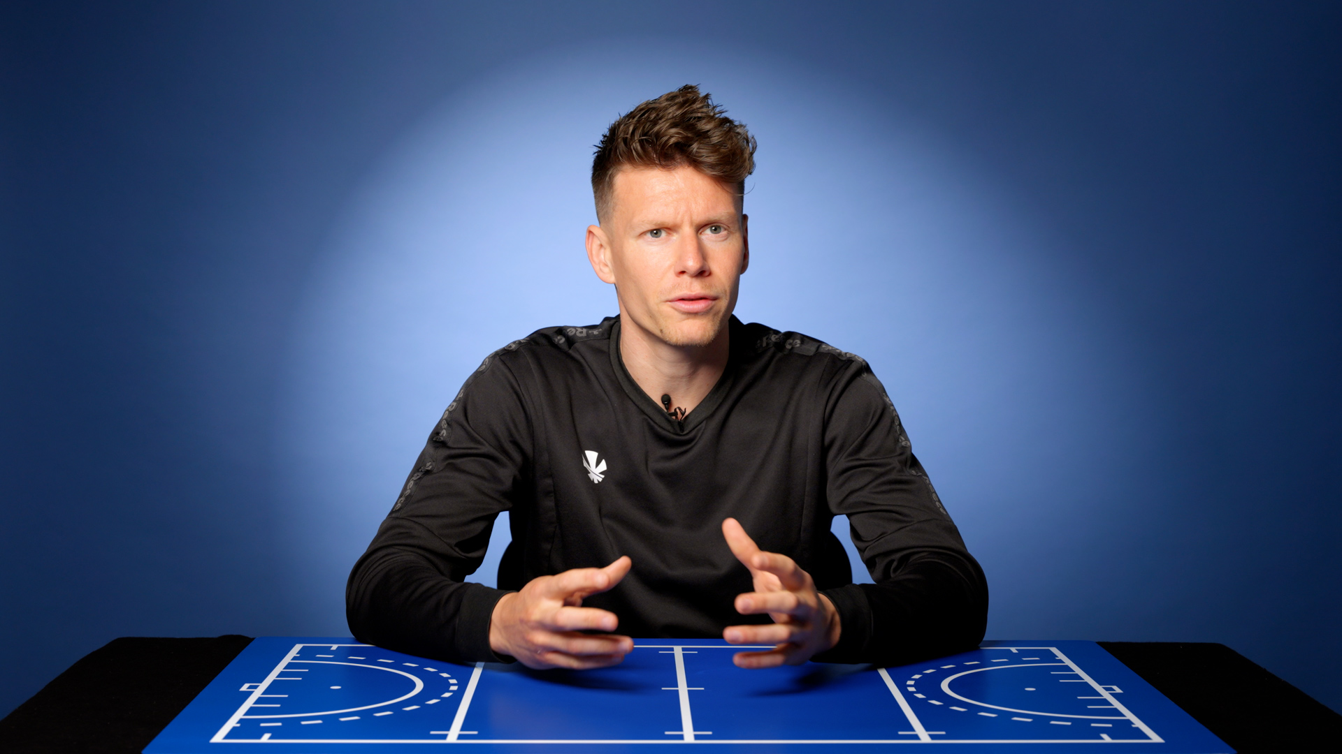 Hockey coach Jelle Galema teaching field hockey tactics on a tactical board.
