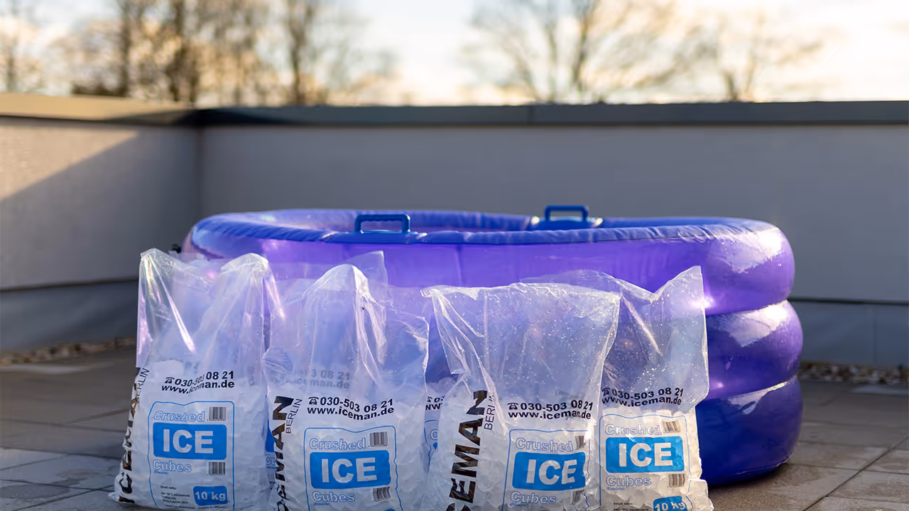 Mehrere Beutel mit zerstoßenem Eis vor einem aufblasbaren blauen Pool auf einer Terrasse.