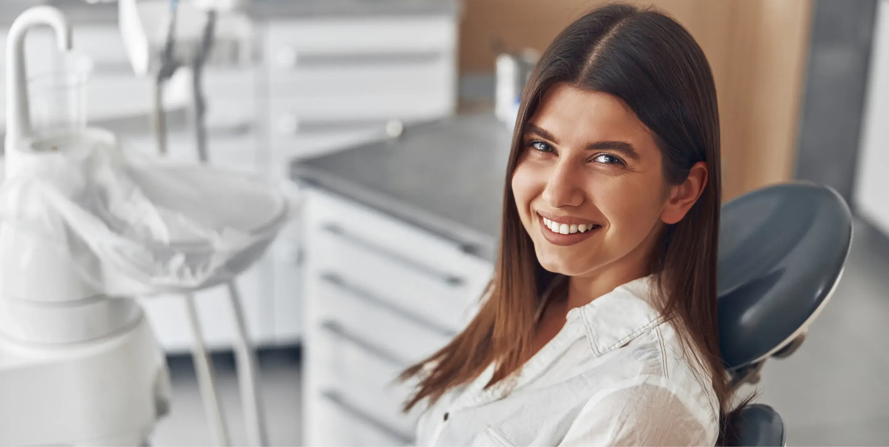 Woman smiling while sitting in a dental chair at a clinic.