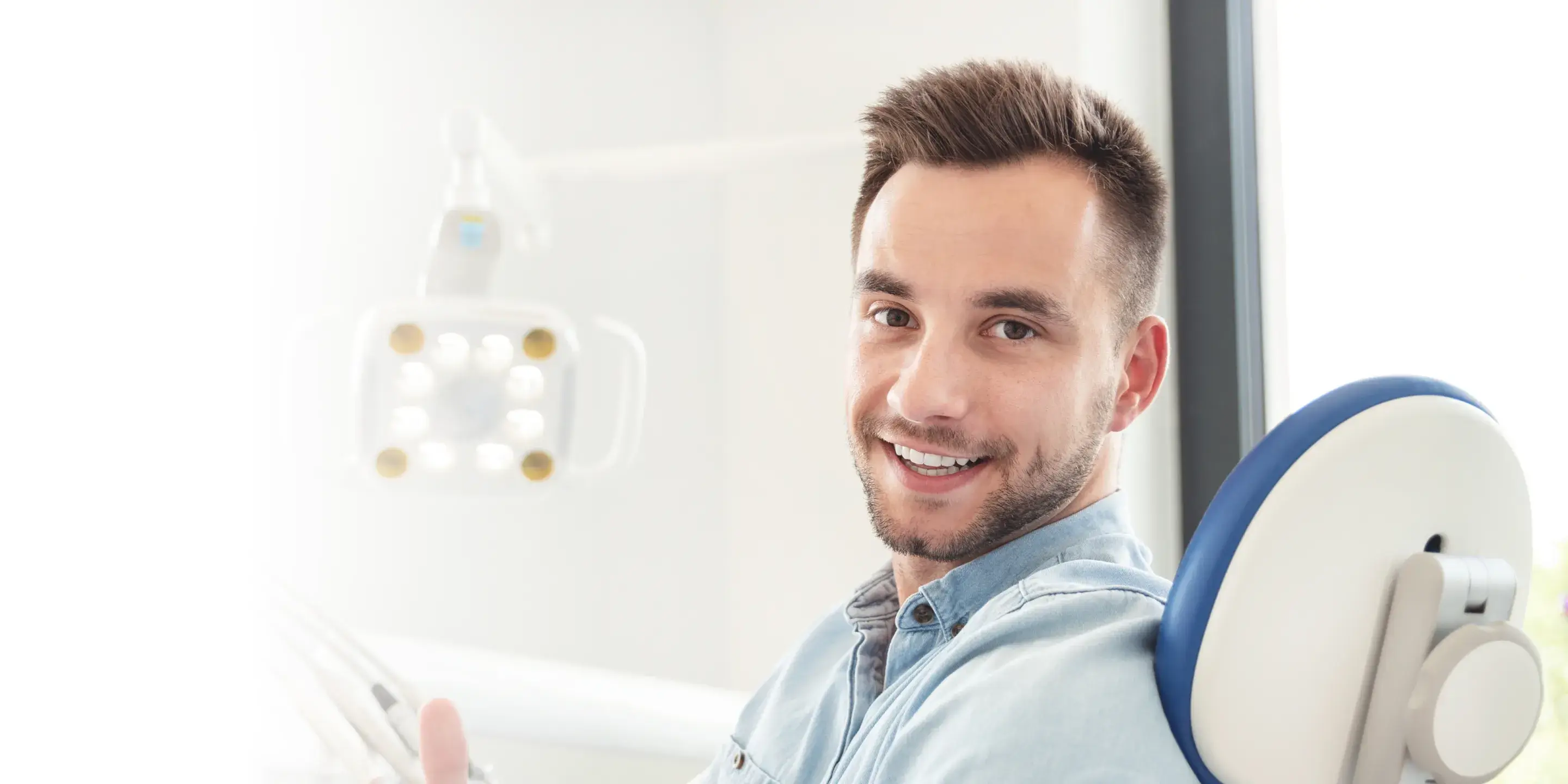 A man smiles while sitting in a dental chair at a dentist's office.