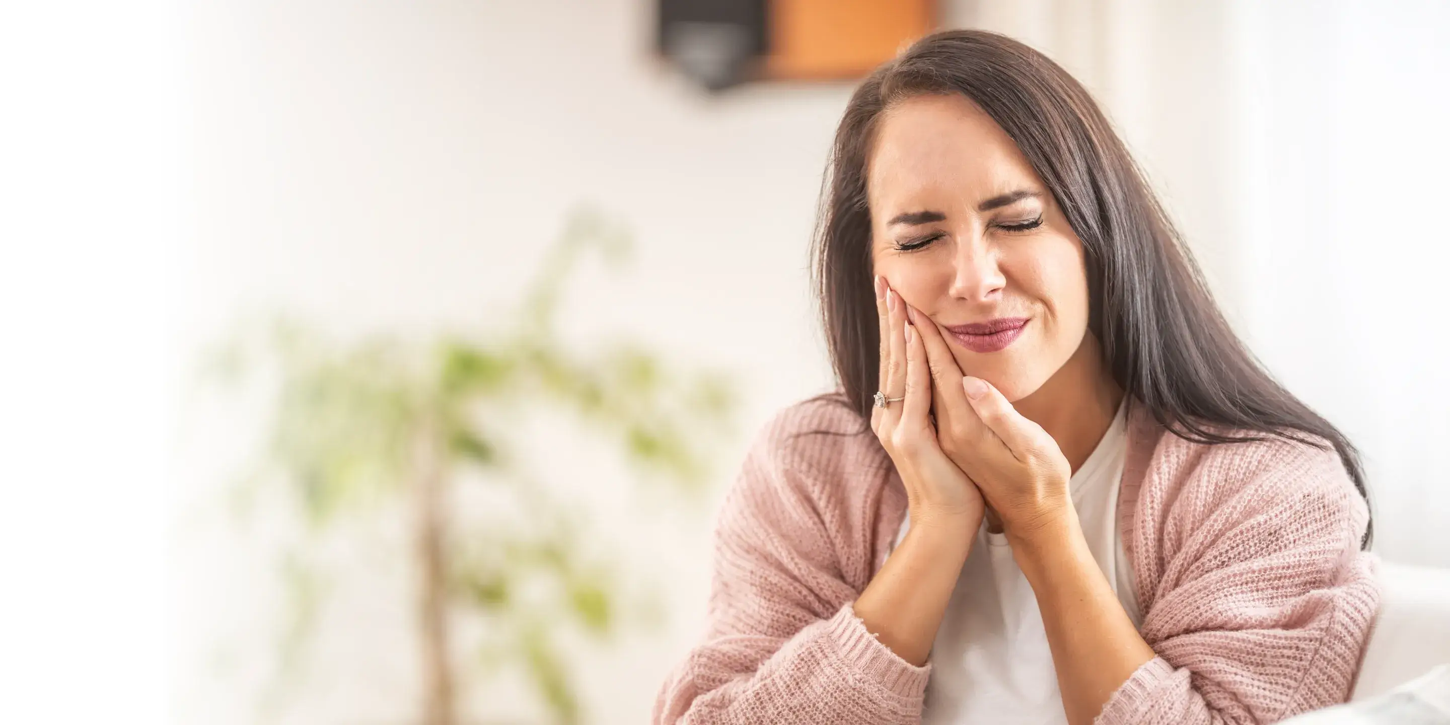 A woman sitting on a couch holding her hands together.