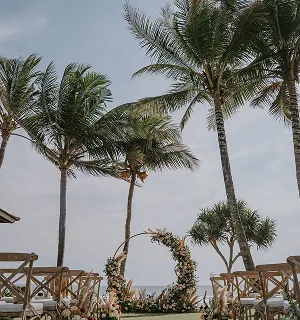 Arche de mariage à Bali, décorée de fleurs balinaises avec des palmiers en arrière-plan sous un ciel bleu.