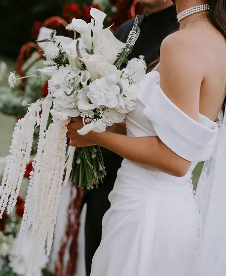 Robe de mariée off-shoulder avec bouquet de lys et gypsophile lors d'un mariage sur-mesure à Bali.